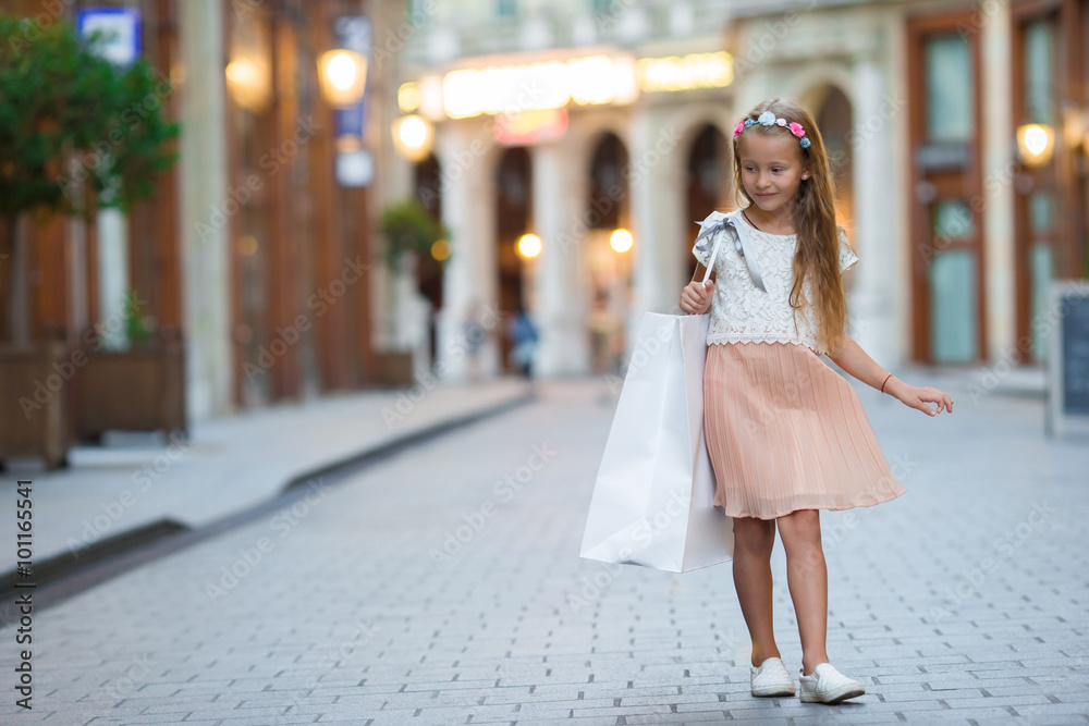 Little girl walking with shopping bags outdoors in european city