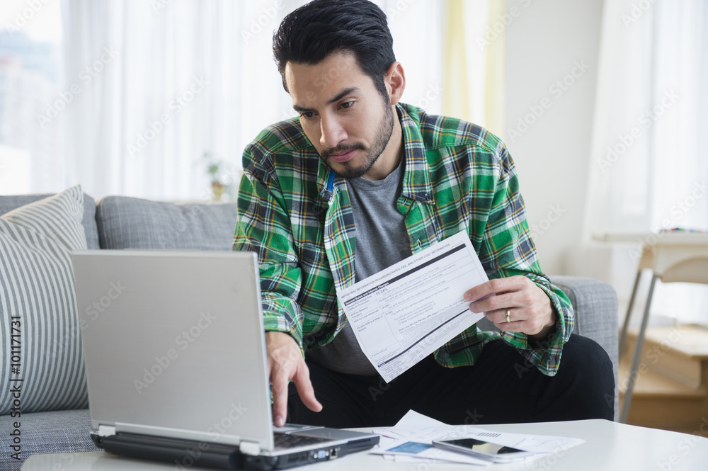 Mixed race man paying bills in living room Mixed race man paying bills in living room