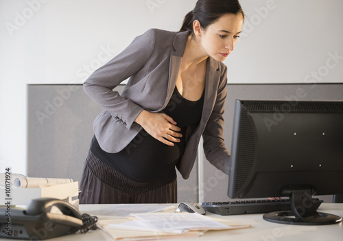 Pregnant Caucasian businesswoman working in office