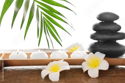 Spa stones with candles  plumeria and bamboo  isolated on white