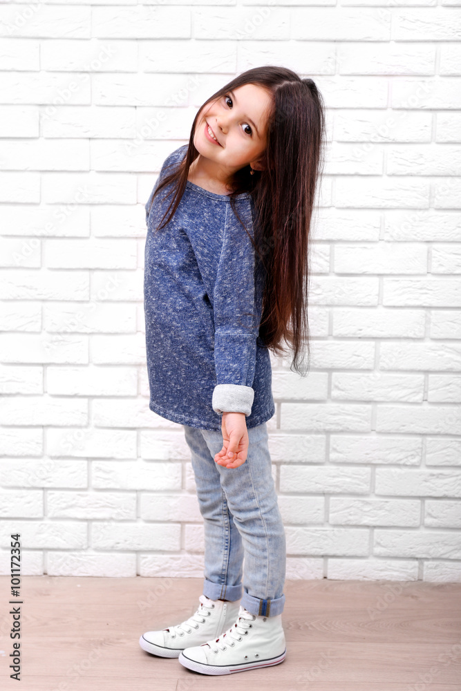 Little girl on a white brick wall background Little girl on a white brick wall background