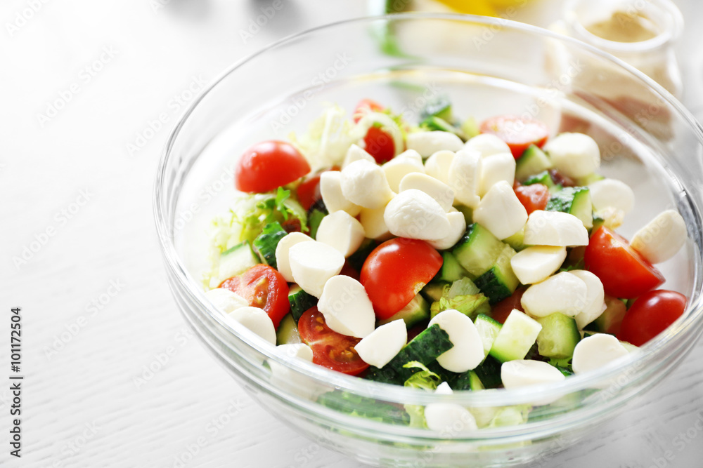 Tasty salad in glass dish on color wooden table background Tasty salad in glass dish on color wooden table background