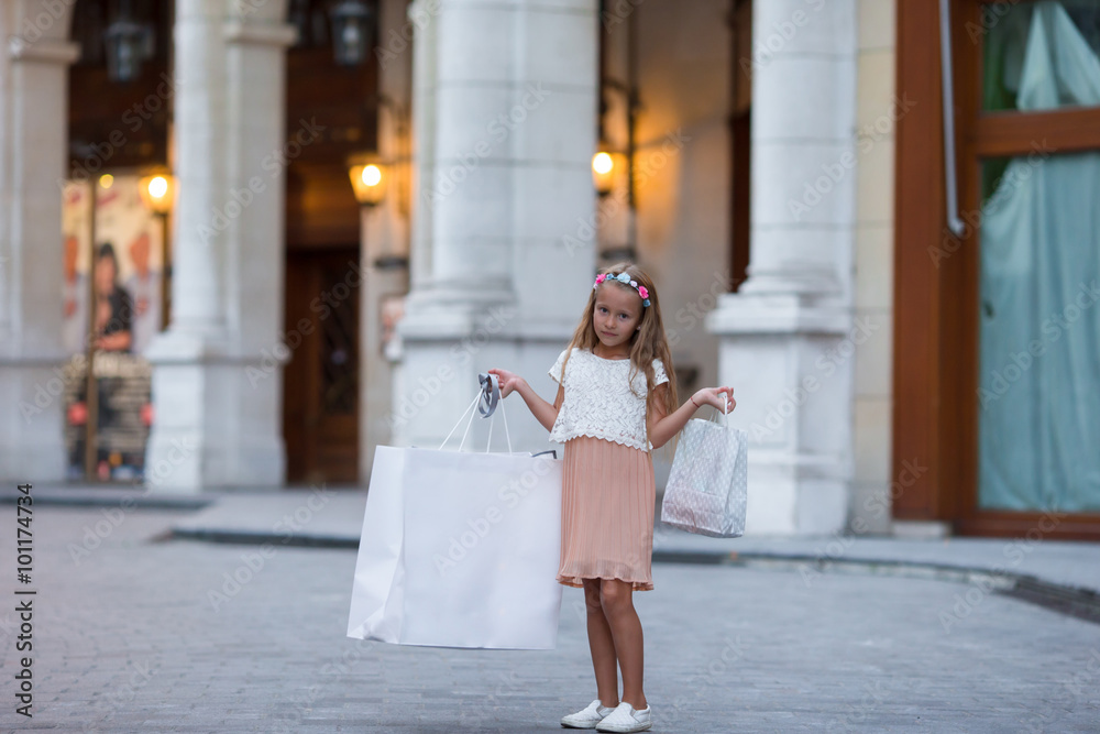 Adorable little girl walking with shopping bags in Paris outdoors
