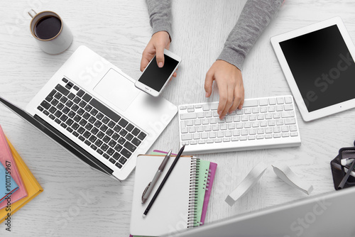 Concept of using electronics. Businesswoman works at office. Computer, laptop, tablet, cup of coffee and other things on the table. Top view