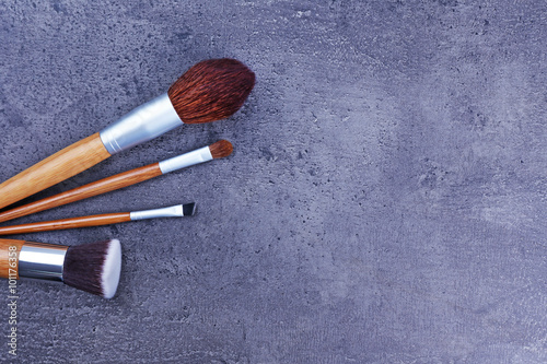 Assortment of make-up brushes, on grey background