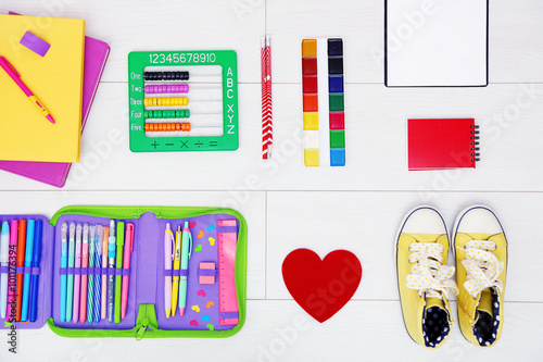 School set with heart, shoes and supplies on light wooden background