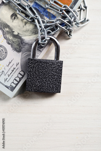 Dollars currency with lock and chain on wooden table background