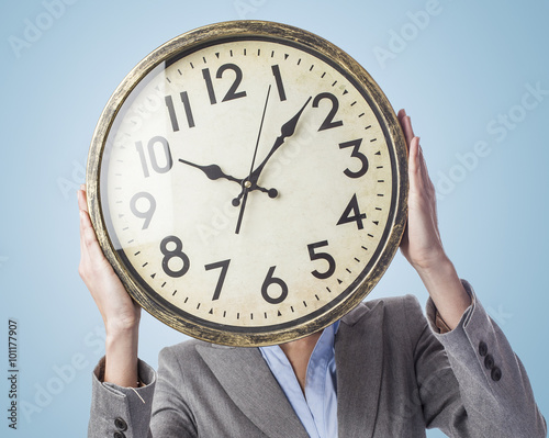 portrait of a business young woman holding a clock in front of her face