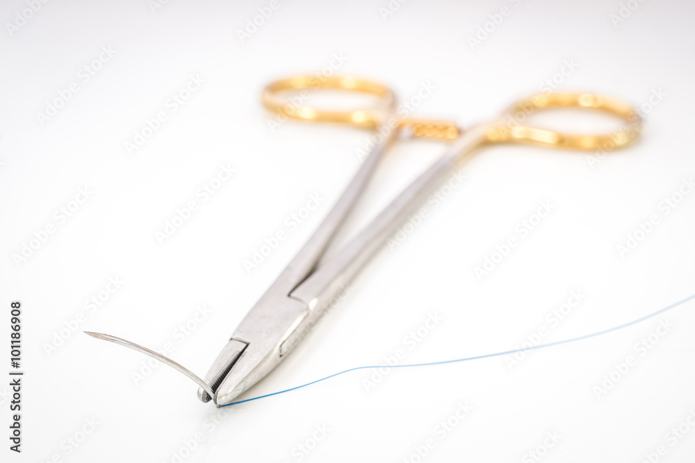 Close up of needle holder with suture and needle Close up of needle holder with suture and needle