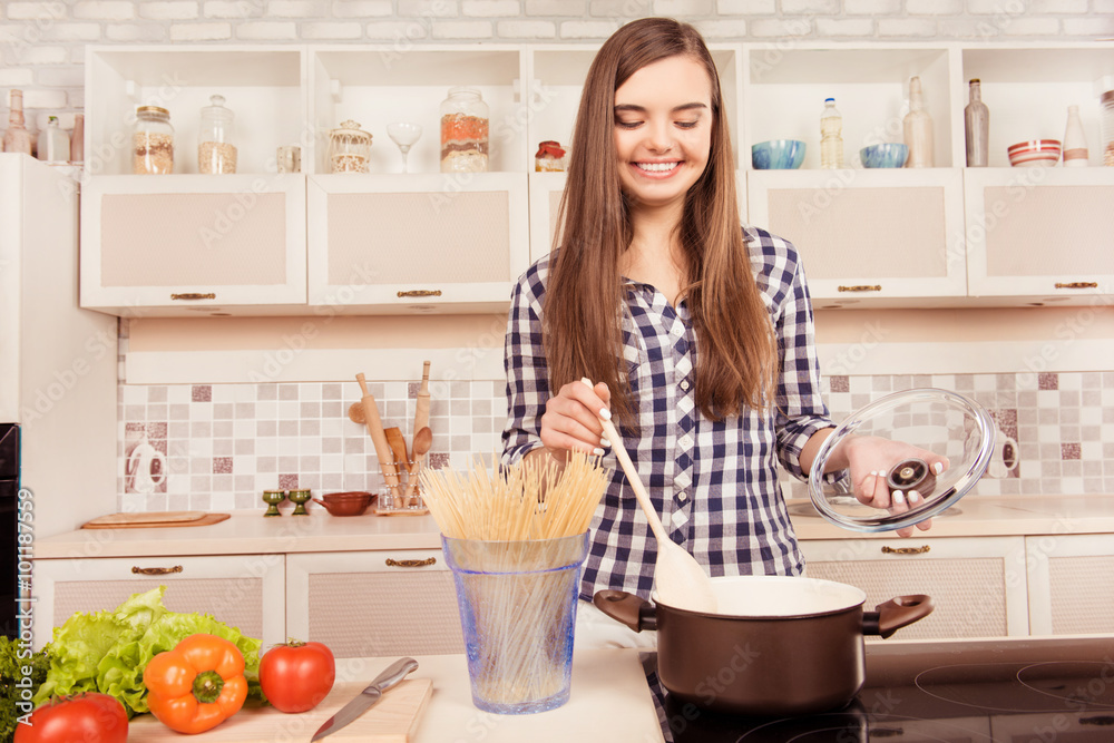 Happy  young woman  boiling  spaghetti in the kitchen