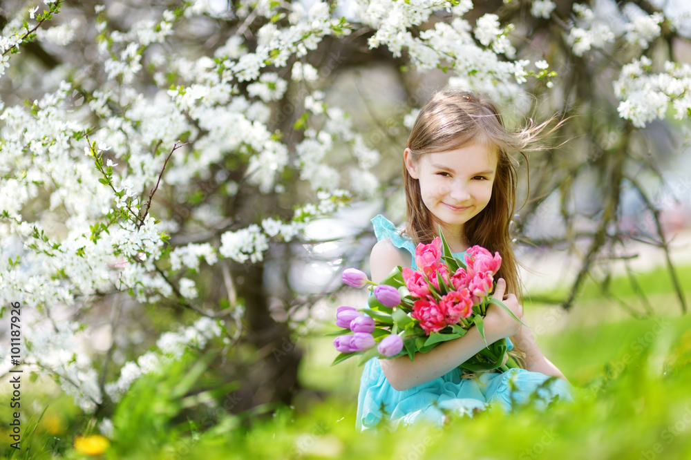 Adorable little girl holding tulips for her mother in cherry garden Adorable little girl holding tulips for her mother in cherry garden