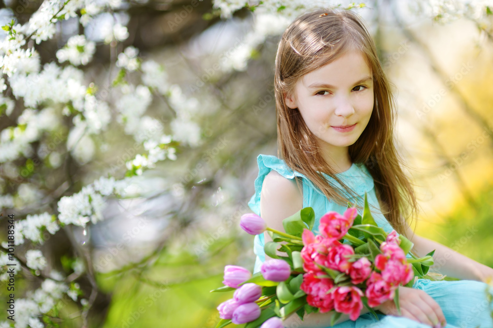 Adorable little girl holding tulips for her mother in cherry garden Adorable little girl holding tulips for her mother in cherry garden