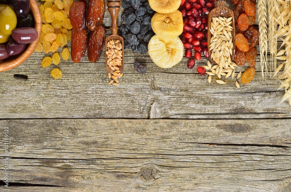 Mix of dried fruits, barley, wheat, olives, pomegranate on wooden table - symbols of judaic holiday Tu Bishvat. Copyspace background.Top view Mix of dried fruits, barley, wheat, olives, pomegranate on wooden table - symbols of judaic holiday Tu Bishvat. Copyspace background.Top view