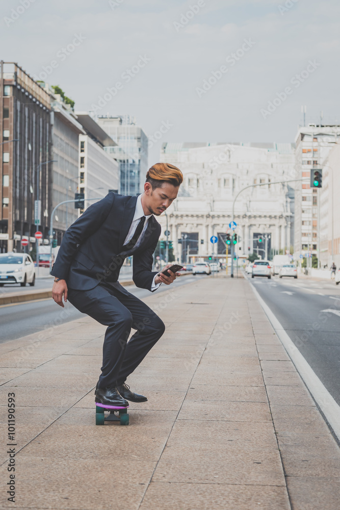 Young handsome Asian model riding his skateboard