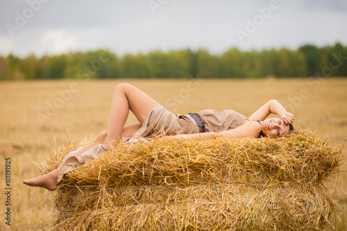 Молодая красивая девушка лежит на стоге сена