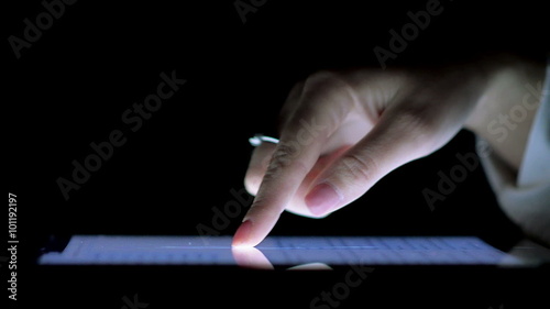 Close-Up of Female Hand on the Ipad Screen in the Dark