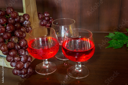 Glasses of wine and grapes in wooden crate on wooden background