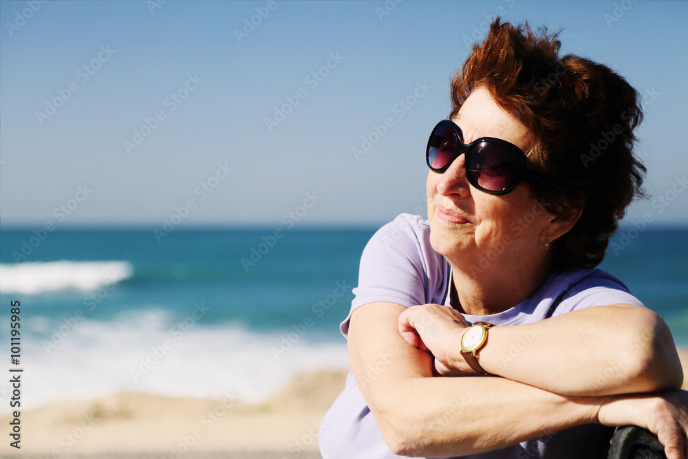 Portrait of happy senior woman sitting neat the sea