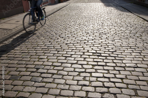 Cyclist and Shadow on Cobbled Stones