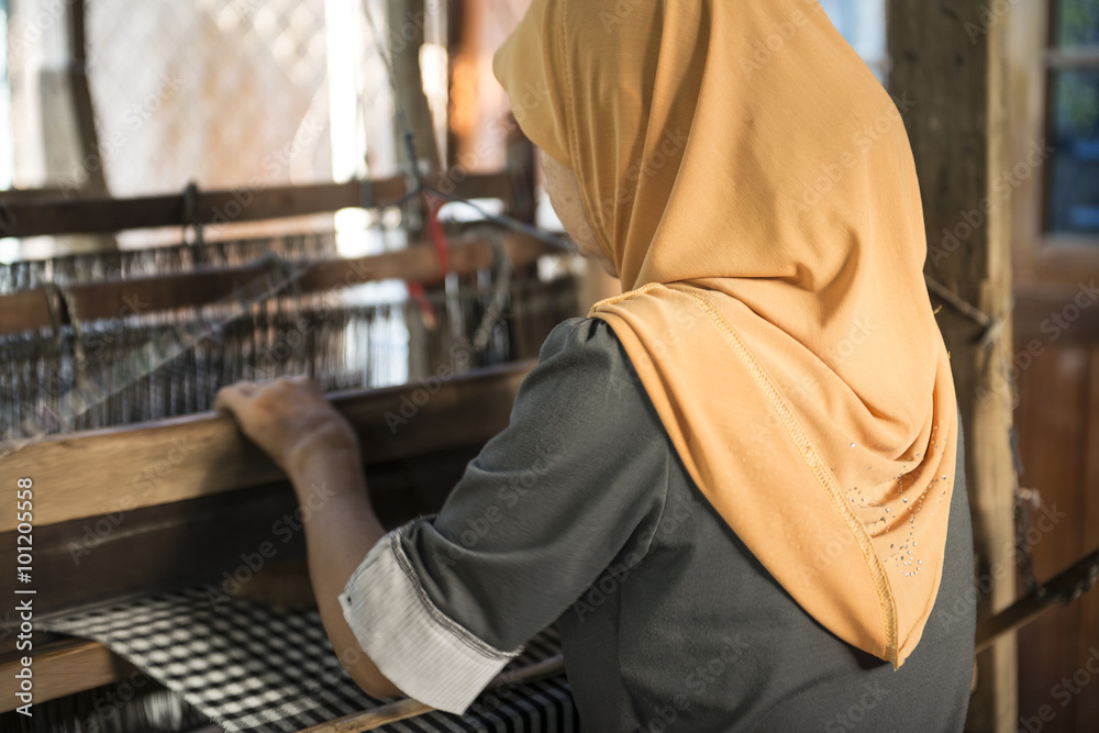 Mujer musulmana de espalda trabajando en un telar manual. Vietnam