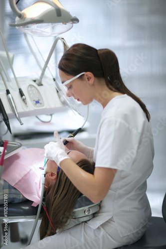 Profile of a young dentist providing restorative teeth's treatment