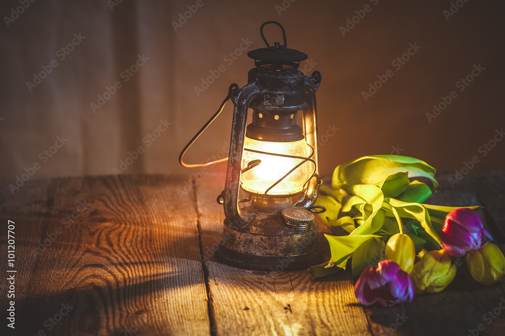 bouquet of tulips at the lighted lamp on a wooden table