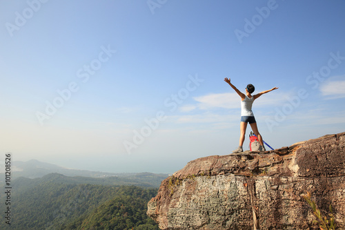 cheering woman hiker open arms at mountain peak