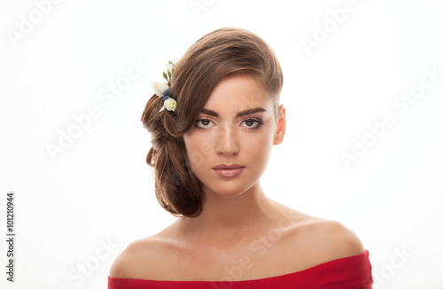 Closeup beauty portrait of young adorable brunette woman in red shirt with bare shoulders showing low bun hairstyle and trendy natural makeup on white studio background