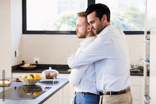 Gay couple with eyes closed hugging 