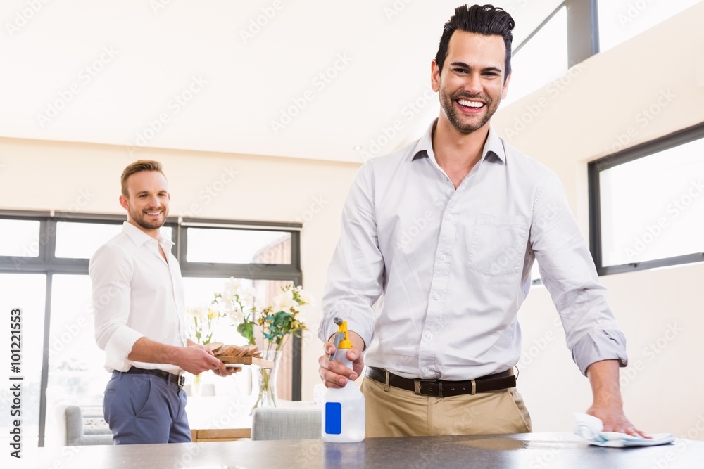 Smiling gay couple cleaning living room Smiling gay couple cleaning living room