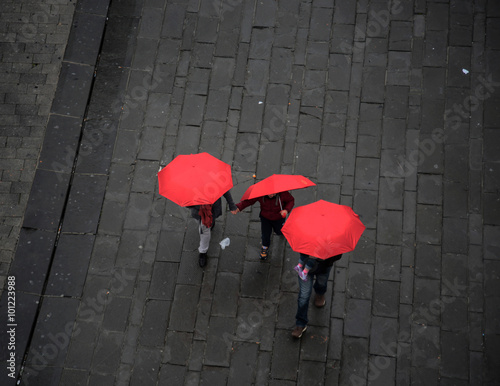 The people with red umbrellas walking on the rain in old town