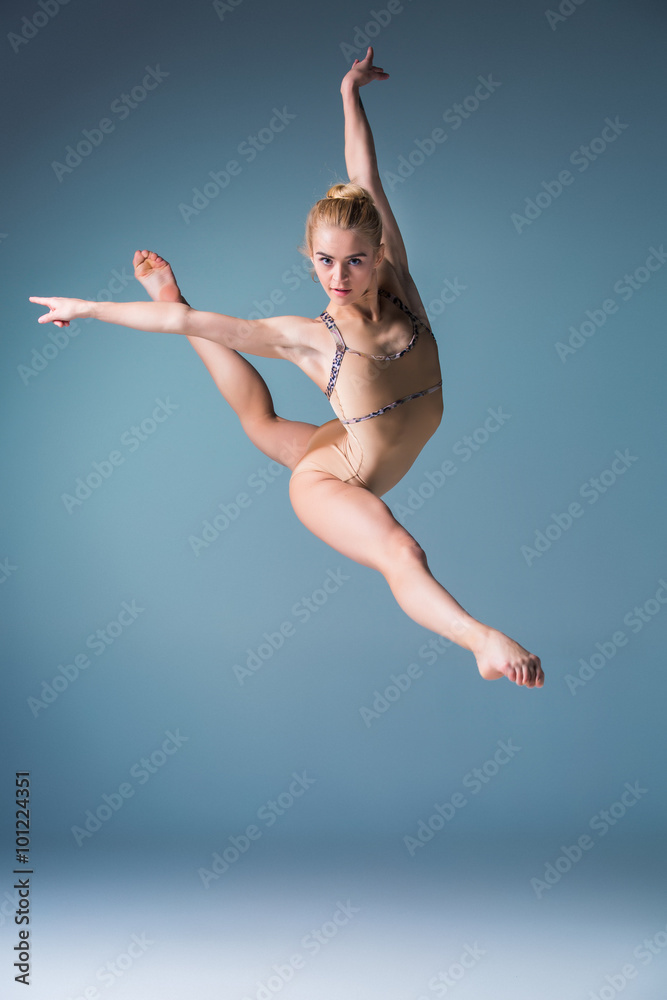 Naklejka premium Young beautiful modern style dancer jumping on a studio background