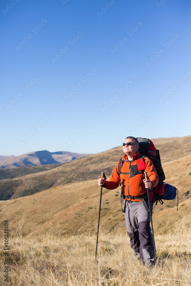 Man hiking in the mountains with a backpack and tent.