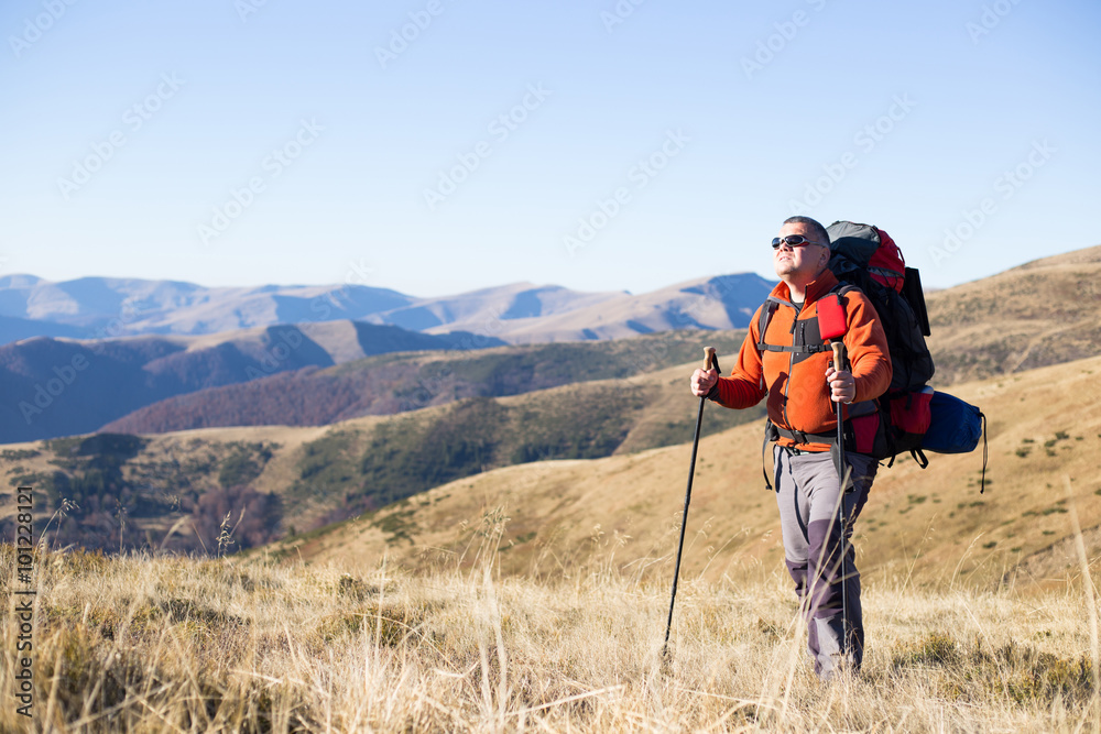 Man hiking in the mountains with a backpack and tent.