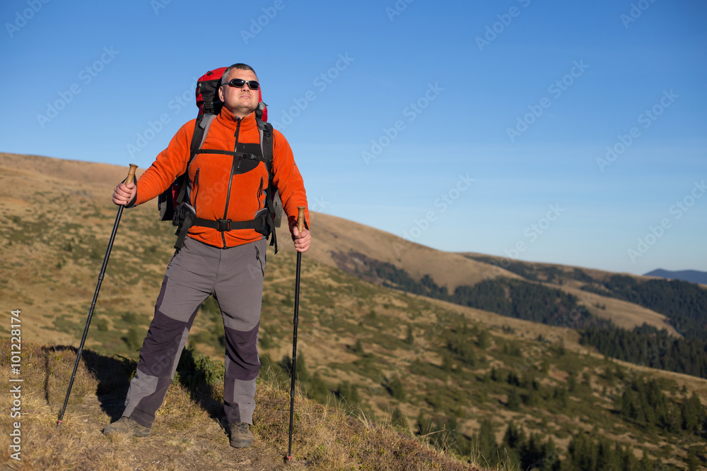 Man hiking in the mountains with a backpack and tent.