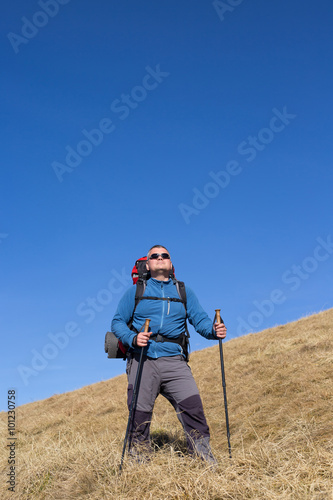 Man hiking in the mountains with a backpack and tent.