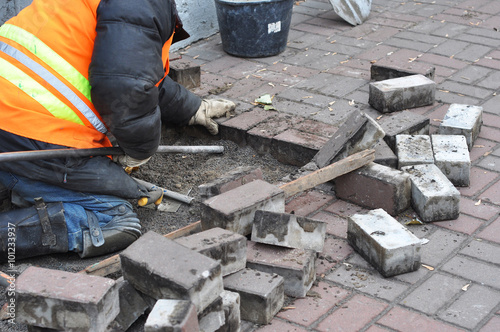 A worker remove and repair concrete paving blocks.