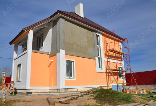 Construction or repair of the rural house with balcony, eaves, windows, chimney, roofing, fixing facade, insulation, plastering and using color. House construction. photo