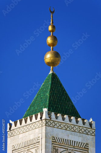 Tunisia. The medina of Tunis. The top of minaret Zitouna Mosque crowned decorative spire (helmet) with crescent moon shape symbol photo