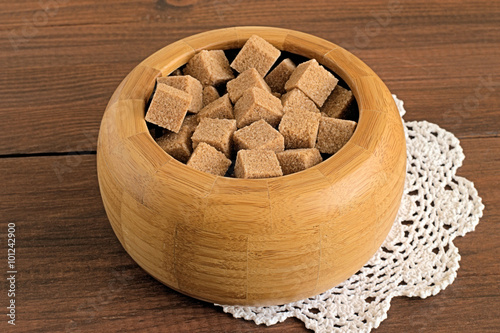 Sugar. Brown sugar in a round sugar bowl on a brown wooden background. 