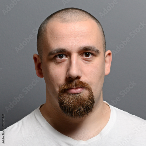 Portrait of a young man standing against gray background