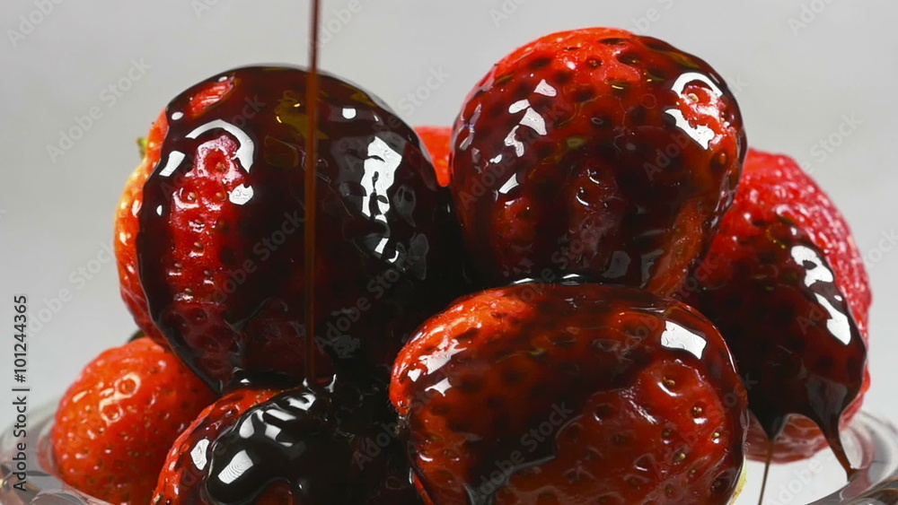 Delicious melted chocolate syrup pouring over strawberries in reverse