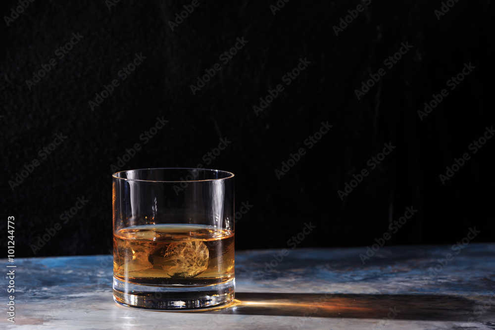 Glass of whiskey with ice on the table