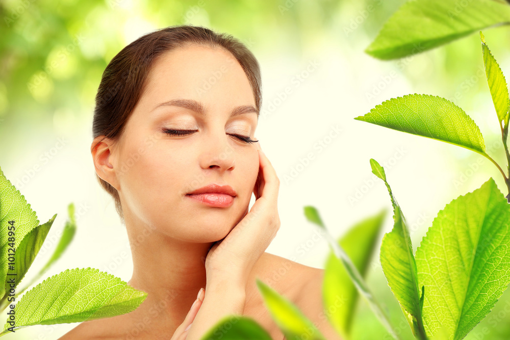 Portrait of young beautiful woman, on green nature background with leaves