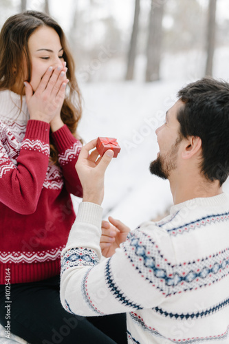 Handsome caucasian man doing a marriage proposal on bright winter day in the park for the valentines day
