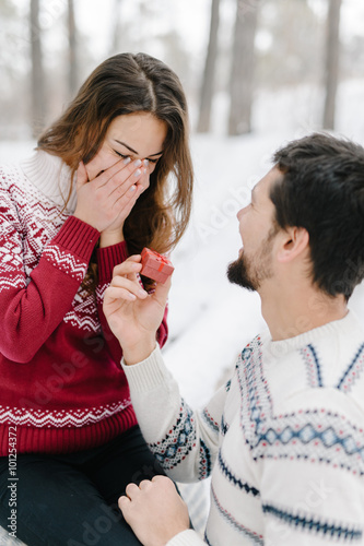 Handsome caucasian man doing a marriage proposal on bright winter day in the park for the valentines day
