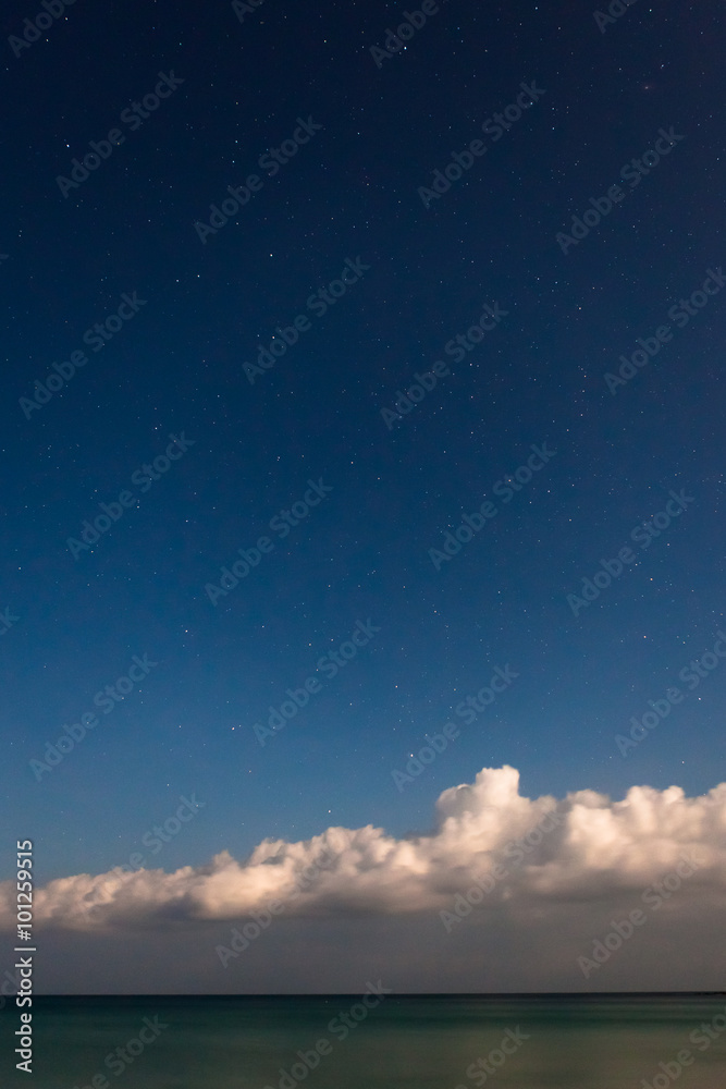 Starry sky with sea and clouds at bottom of image