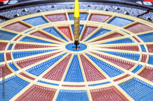 Dart in bulls eye of dartboard photo