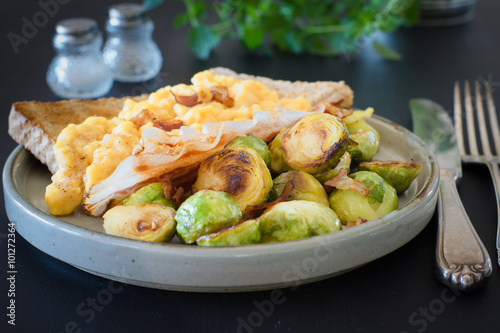 English breakfast with scrambled eggs, roasted brussels sprouts and bacon. Selective focus. photo