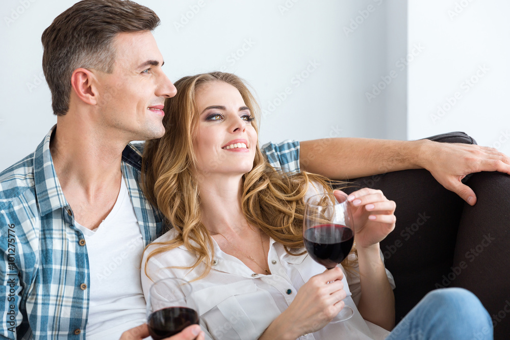 Happy relaxed couple resting and drinking red wine